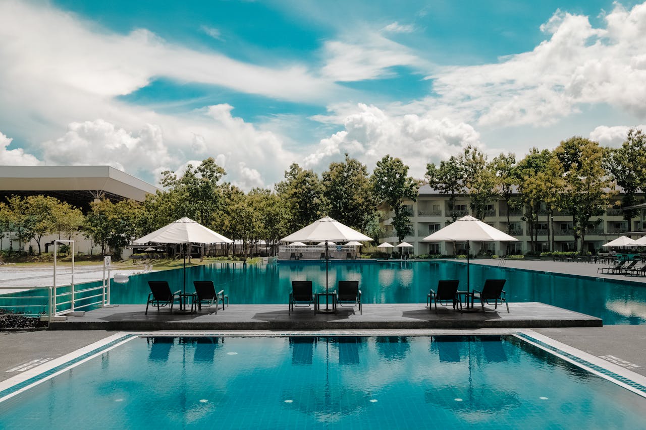 Explore a luxurious resort poolside with umbrellas and lounge chairs under a bright sky, perfect for summer vacations.